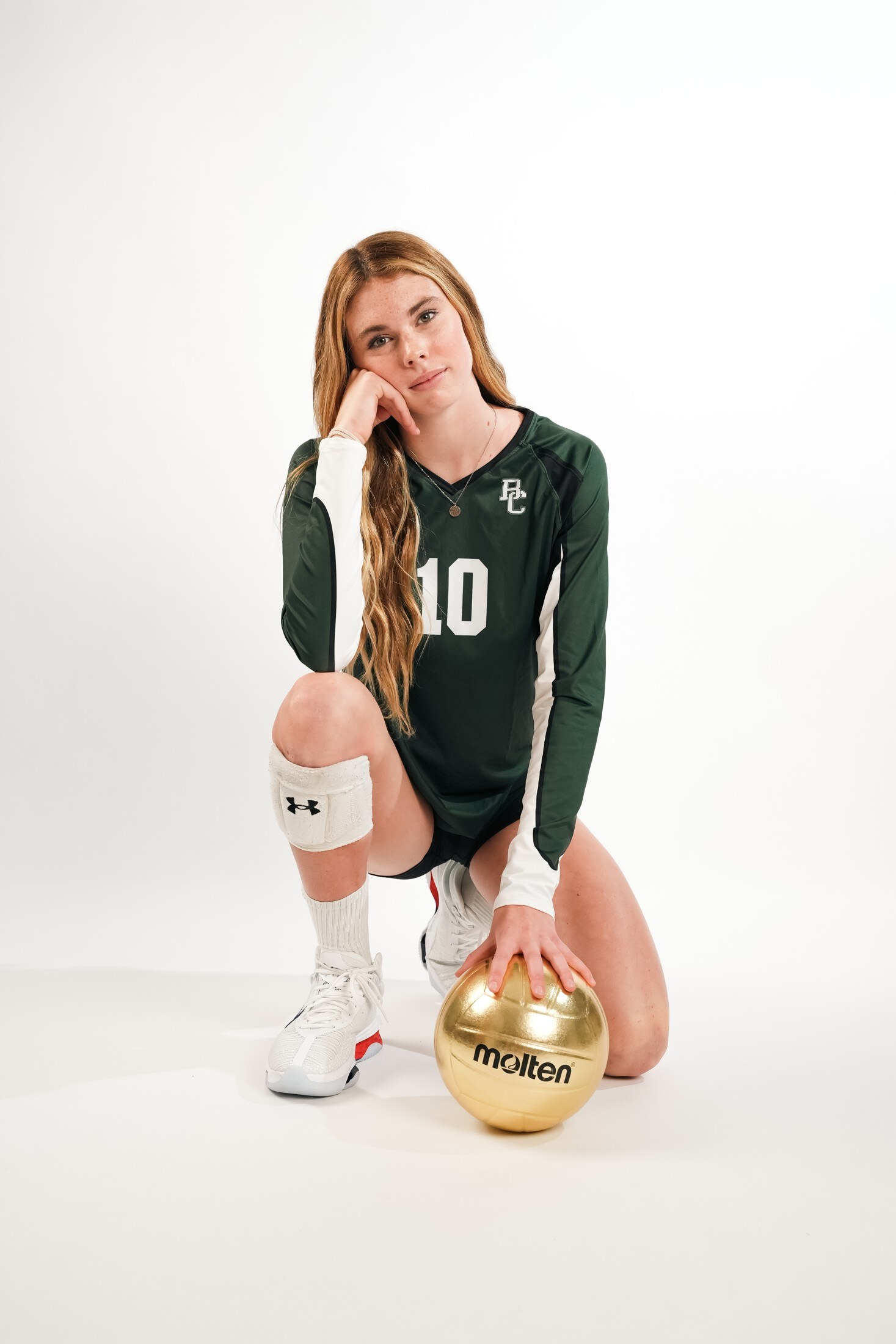 Volleyball player kneeling with a gold ball in the studio