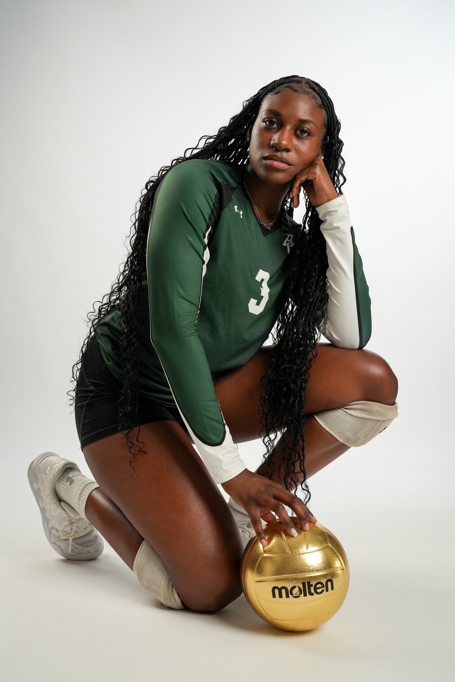 Volleyball player kneeling with a gold volleyball on white