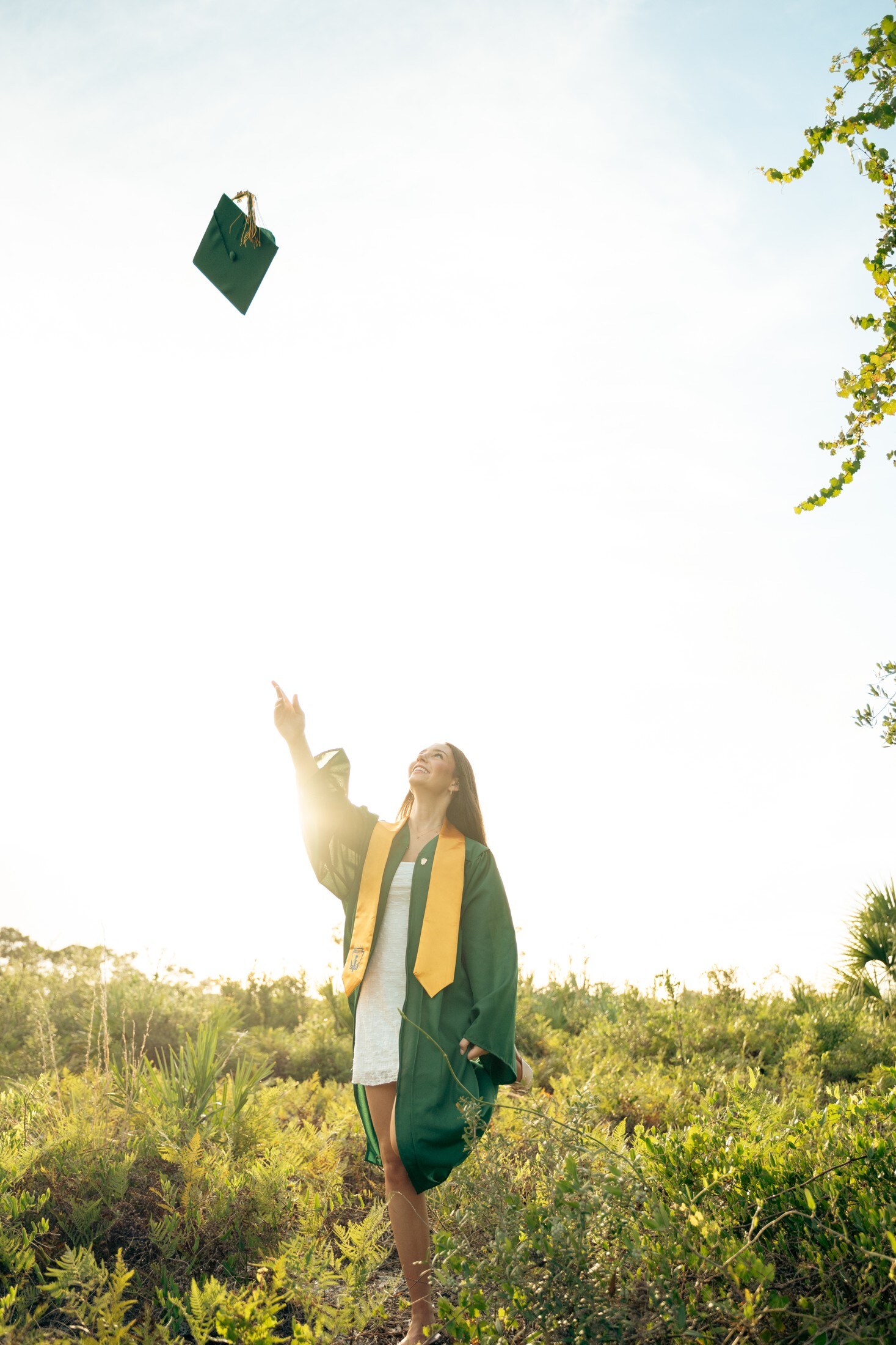 Graduate tossing her cap at golden hour