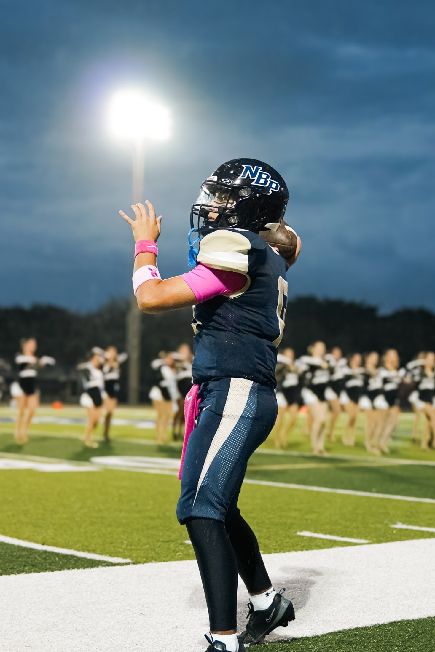 Football player rising for a catch under the stadium lights at night