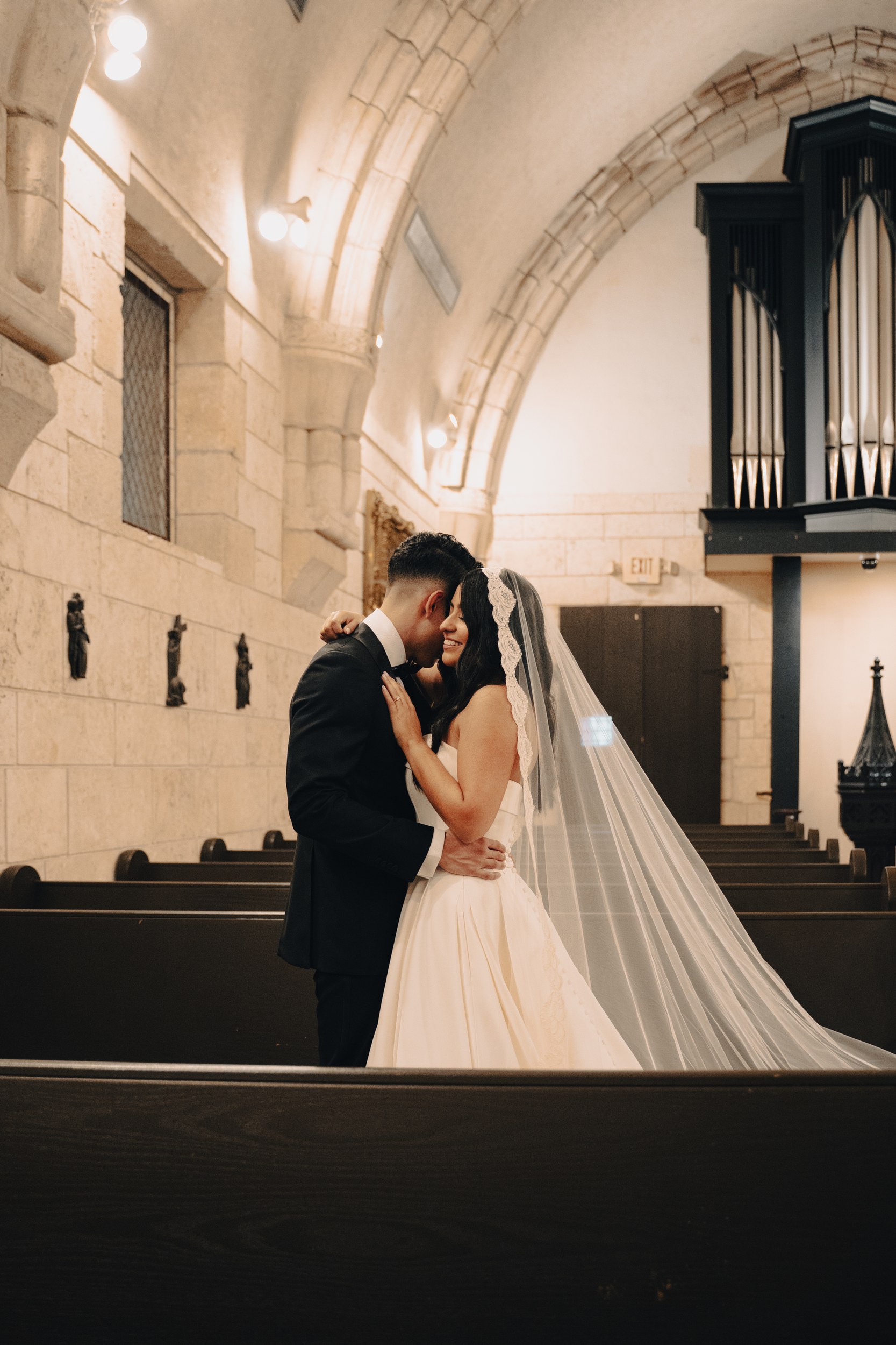 Bride and groom embracing in a stone chapel, photographed by Cameron Valvo